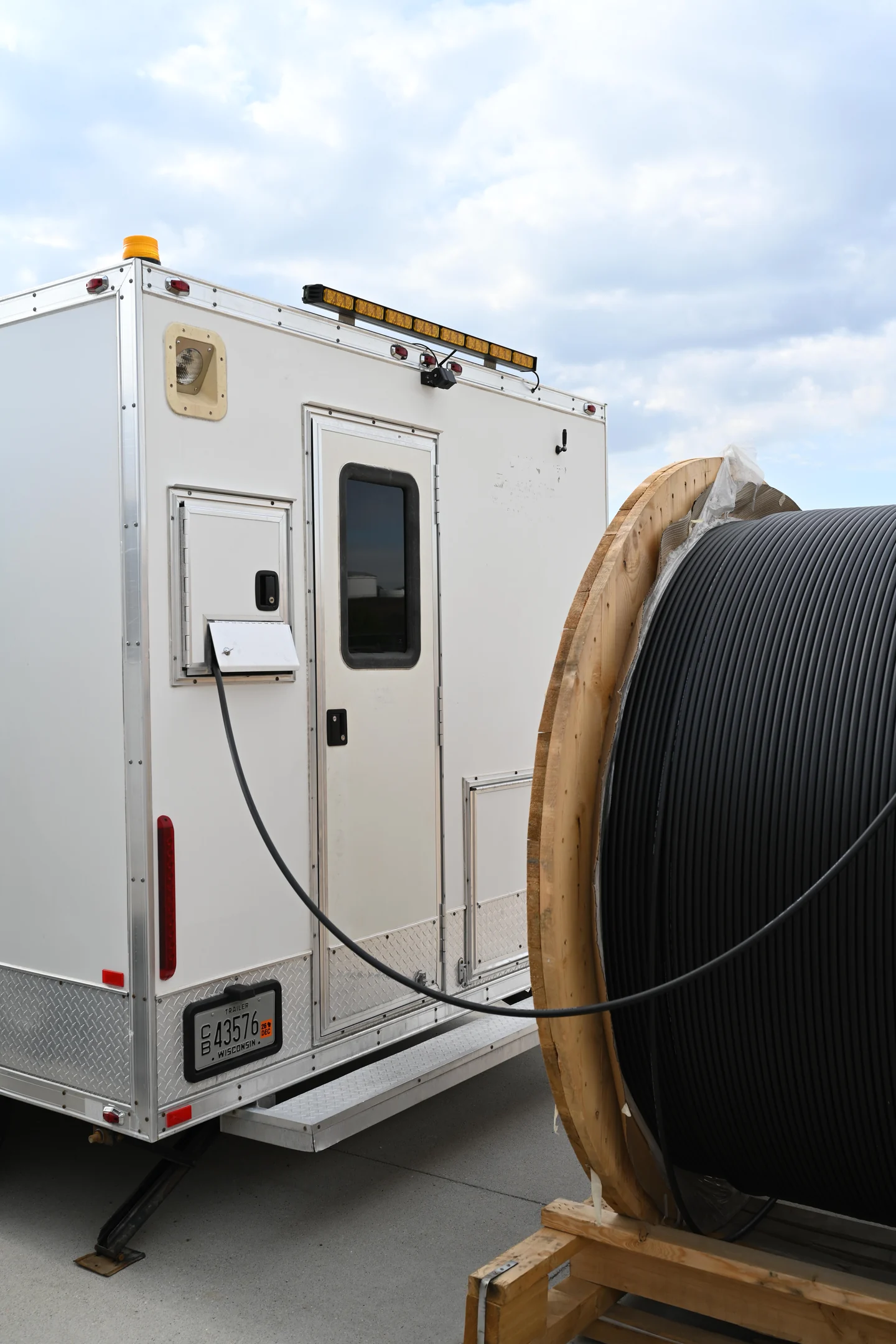 Utility trailer beside a large cable reel